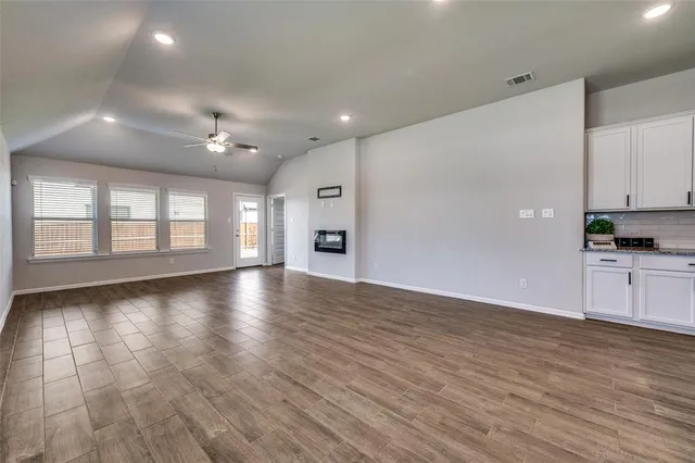 a view of an empty room with window and wooden floor