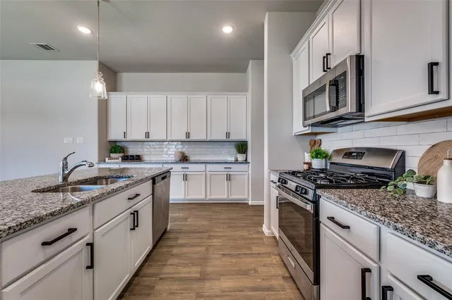 a kitchen with stainless steel appliances granite countertop a stove sink and cabinets