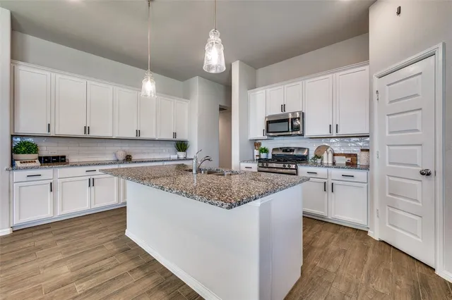 a kitchen with stainless steel appliances granite countertop a stove top oven a sink a microwave and cabinets