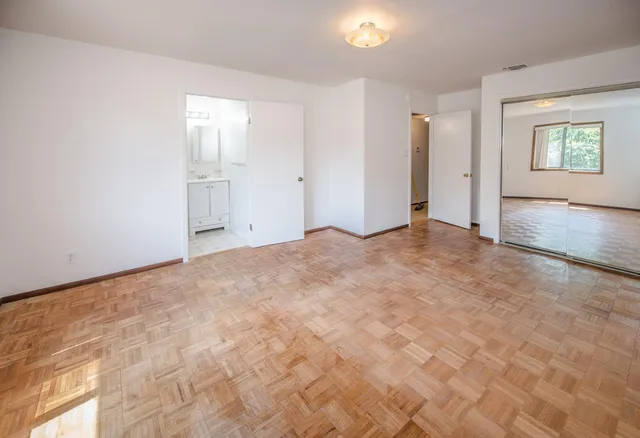 a view of an empty room with window and wooden floor
