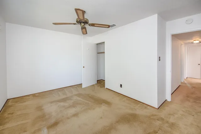 an empty room with a ceiling fan and a window