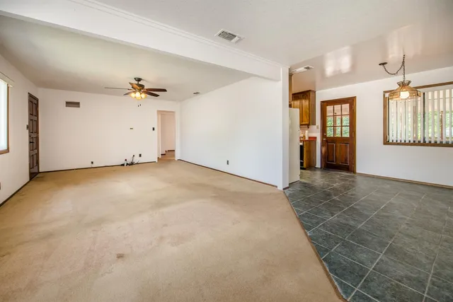 an empty room with chandelier fan and windows