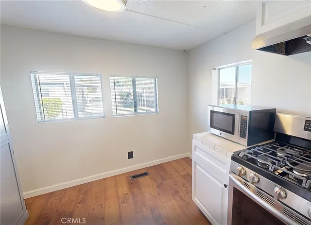 a kitchen with wooden floor and stainless steel appliances