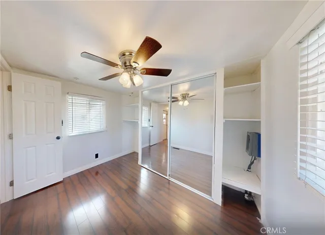 a view of empty room with wooden floor and fan
