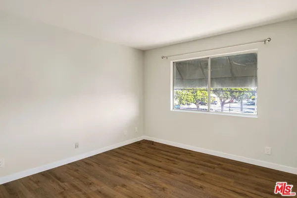 an empty room with wooden floor and a window
