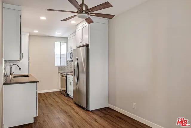a view of a kitchen with a sink refrigerator a ceiling fan and wooden floor