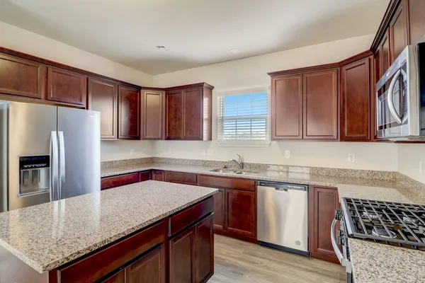 a kitchen with stainless steel appliances granite countertop a sink stove and refrigerator