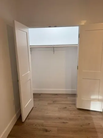 an empty room with wooden floor cabinet and windows