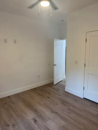 a view of an empty room with window and hardwood floor