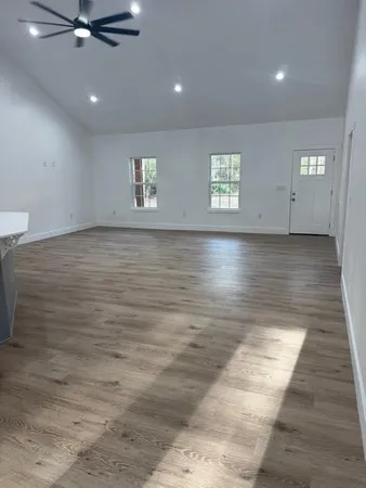 an empty room with wooden floor and windows