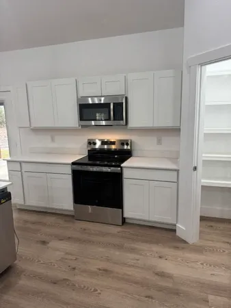 a kitchen with stainless steel appliances a stove a microwave and white cabinets