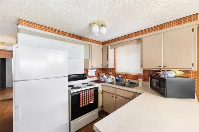 a kitchen with a refrigerator a stove a sink a dining table and chairs