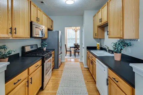 a kitchen with stainless steel appliances granite countertop sink stove top oven and cabinets