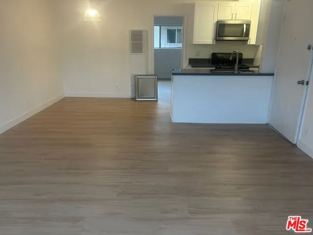 a living room with stainless steel appliances wooden floor and a fireplace