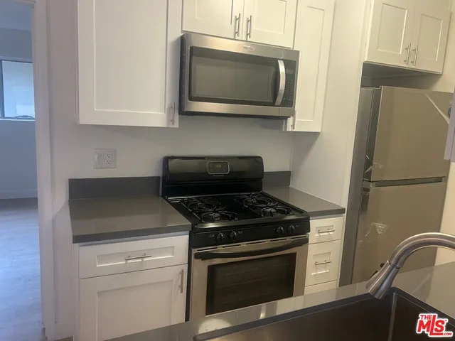 a kitchen with stainless steel appliances granite countertop a stove microwave and refrigerator