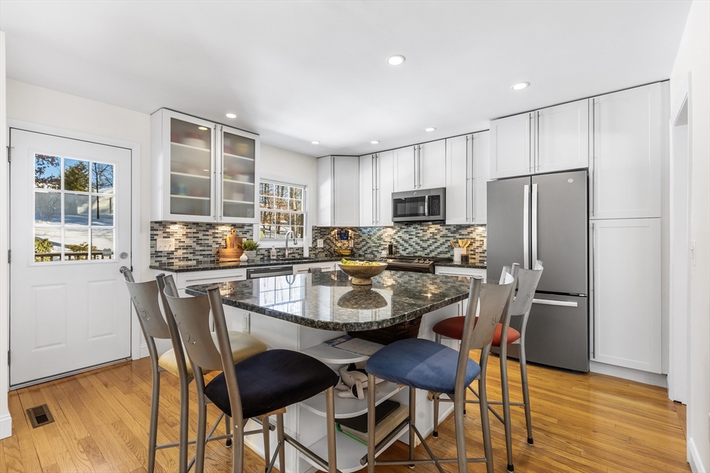 27 Audubon Road Reading, MA 01867 - Photo 12 of 35 a kitchen with stainless steel appliances granite countertop a dining table chairs refrigerator and cabinets