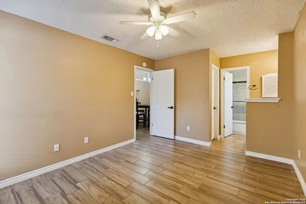 an empty room with wooden floor and a ceiling fan