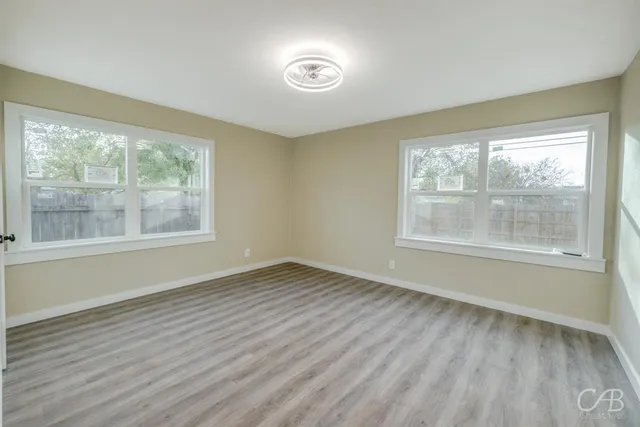 a view of an empty room with wooden floor and a window