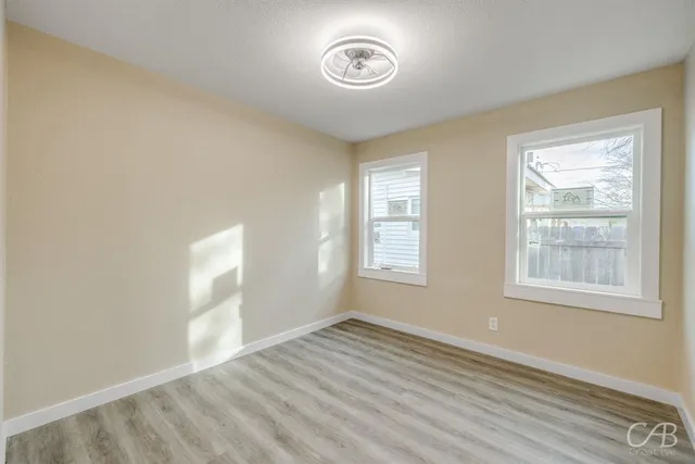 an empty room with wooden floor and windows