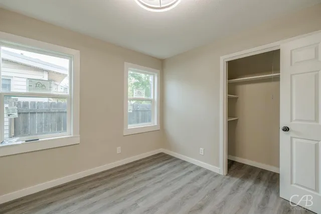 an empty room with wooden floor and windows