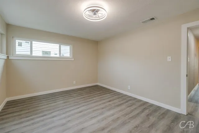 an empty room with wooden floor and a window