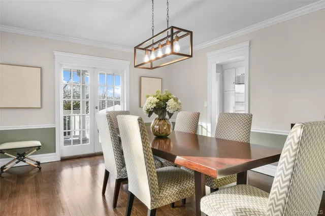 a dining room with furniture a rug a potted plant and wooden floor