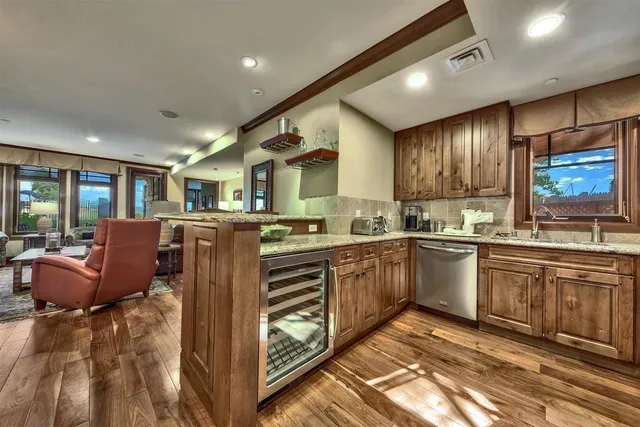 a kitchen with stainless steel appliances granite countertop a refrigerator a sink dishwasher a stove and white cabinets with wooden floor