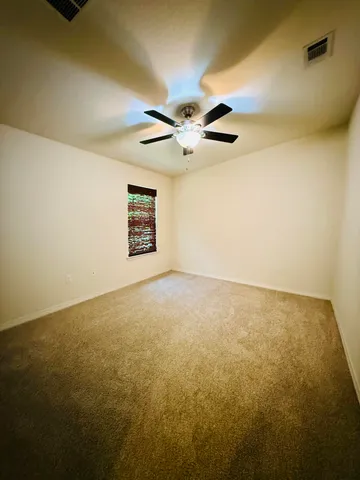an empty room with a ceiling fan and a window