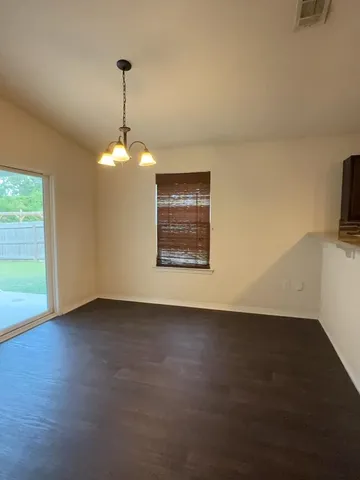a view of an empty room with glass door and wooden floor