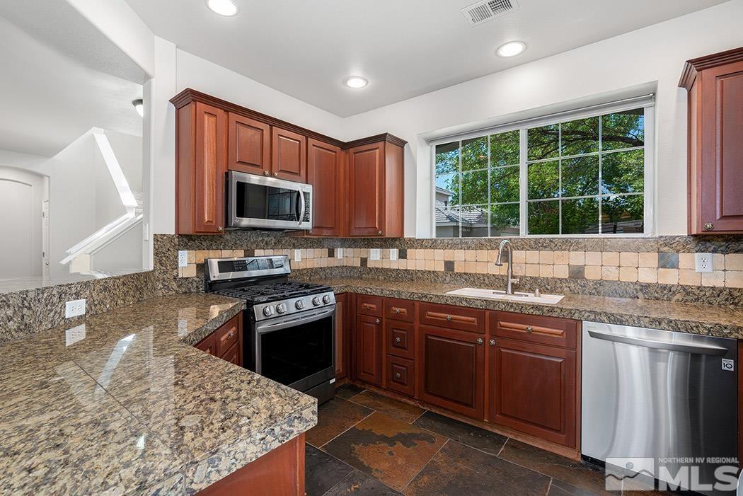 9646 Otter Way Reno, NV 89521 - Photo 10 of 25 a kitchen with granite countertop stainless steel appliances stove microwave and sink