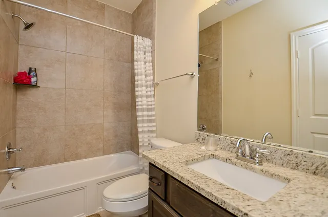 a bathroom with a granite countertop sink a toilet and shower