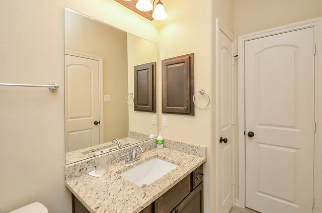 a bathroom with a granite countertop sink and a mirror