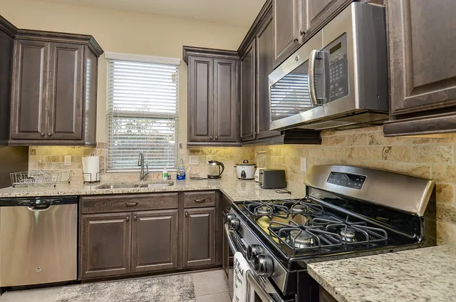 a kitchen with granite countertop a stove sink and cabinets