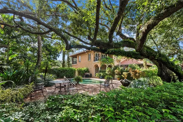 a backyard of a house with table and chairs under an umbrella