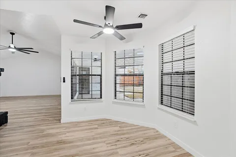 a view of an empty room with a window and wooden floor