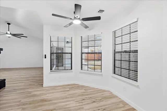 a view of an empty room with a window and wooden floor
