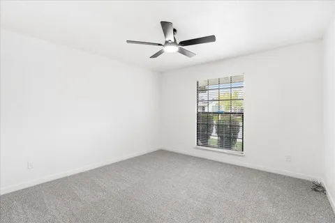 an empty room with windows and ceiling fan