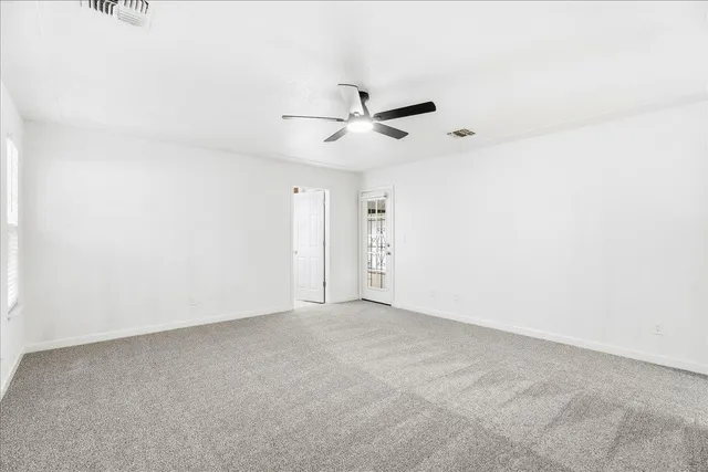 an empty room with a ceiling fan and a window