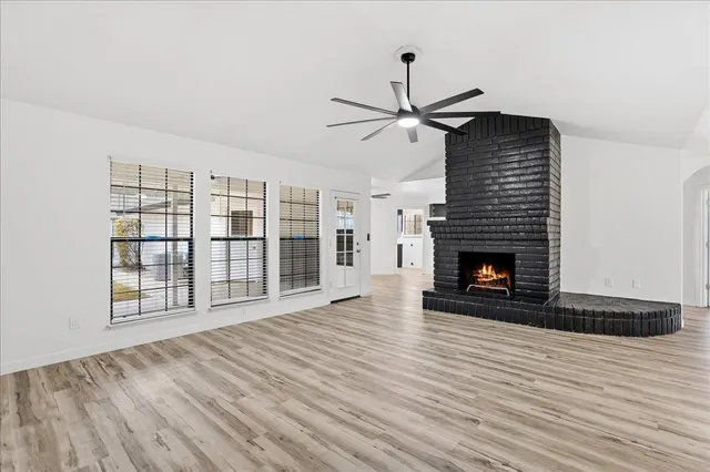 a view of an empty room with wooden floor fireplace and a window