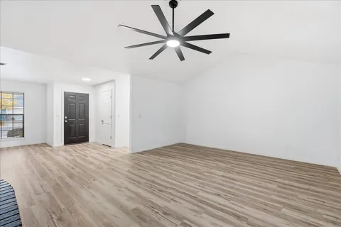 a view of an empty room with window and wooden floor