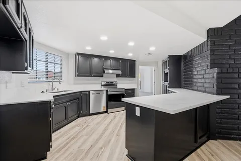 a kitchen with a sink a kitchen island stainless steel appliances cabinets and a window