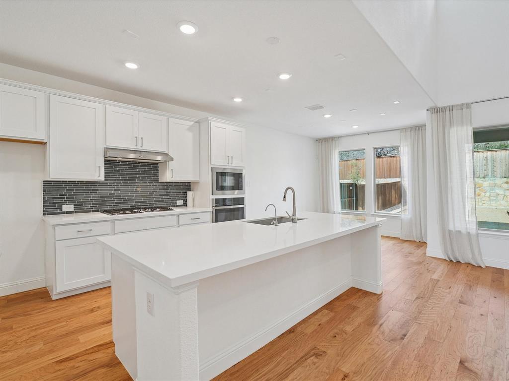 321 Fulton Street Oak Point, TX 75068 - Photo 12 of 36 a large white kitchen with stainless steel appliances granite countertop a stove a sink a refrigerator and white cabinets with wooden floor
