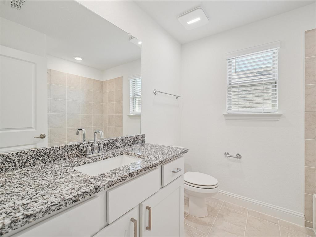 321 Fulton Street Oak Point, TX 75068 - Photo 29 of 36 a bathroom with a granite countertop sink a toilet and a mirror
