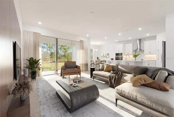 a living room with furniture kitchen view and large windows