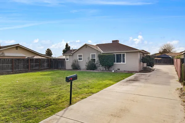 a front view of house with yard and trees in the background