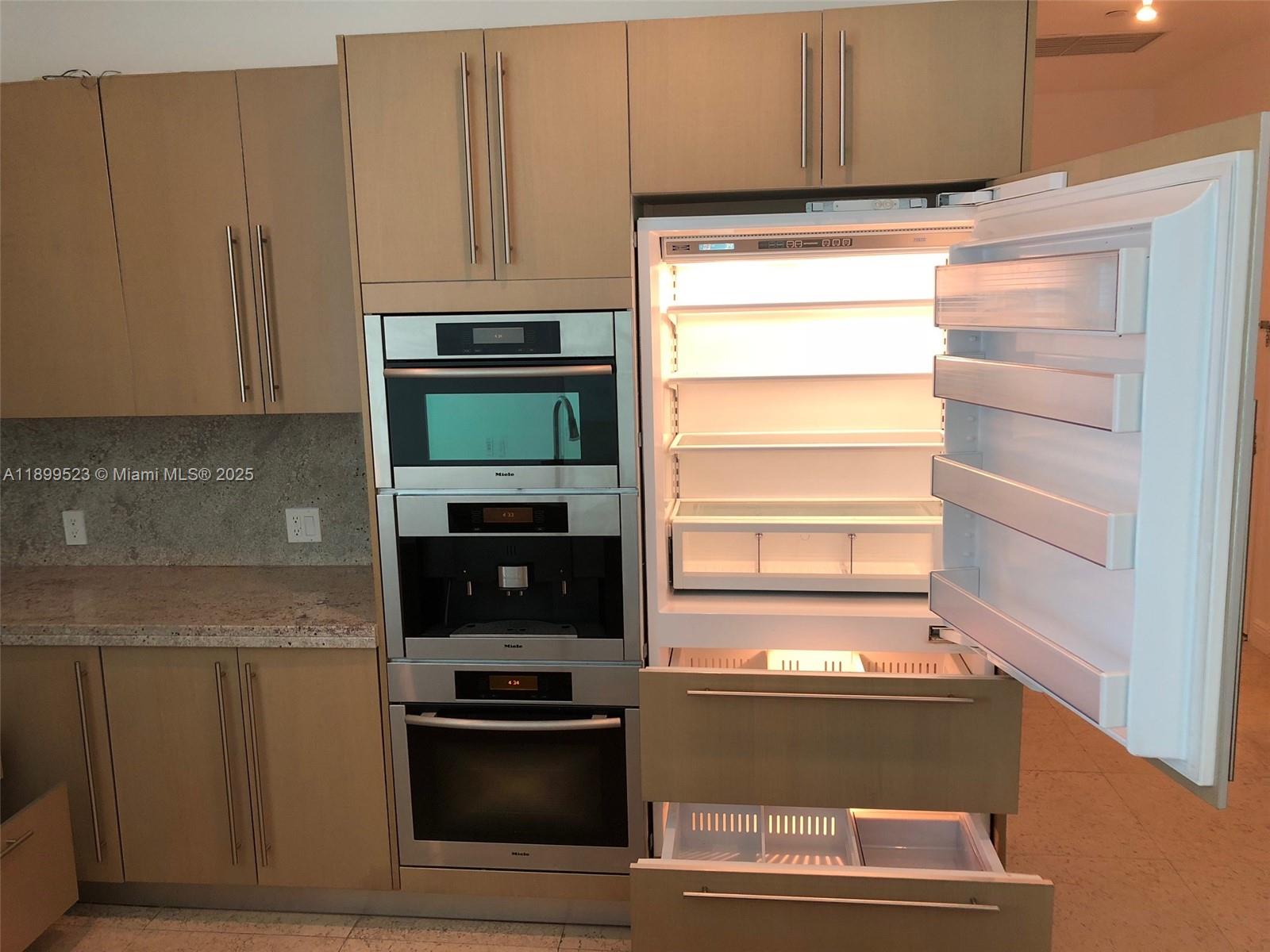 900 Brickell Key Boulevard, Unit 2205 Miami, FL 33131 - Photo 19 of 50 a kitchen with granite countertop a refrigerator stove and cabinets