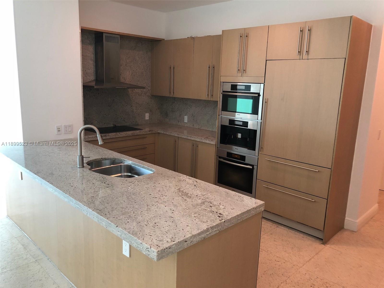 900 Brickell Key Boulevard, Unit 2205 Miami, FL 33131 - Photo 8 of 50 a kitchen with a sink a microwave a refrigerator and cabinets