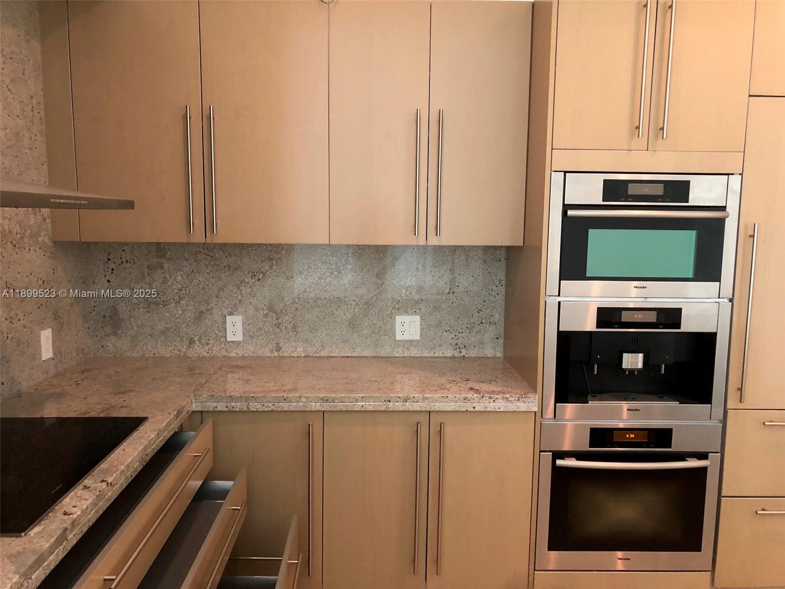900 Brickell Key Boulevard, Unit 2205 Miami, FL 33131 - Photo 9 of 50 a kitchen with appliances a sink and cabinets