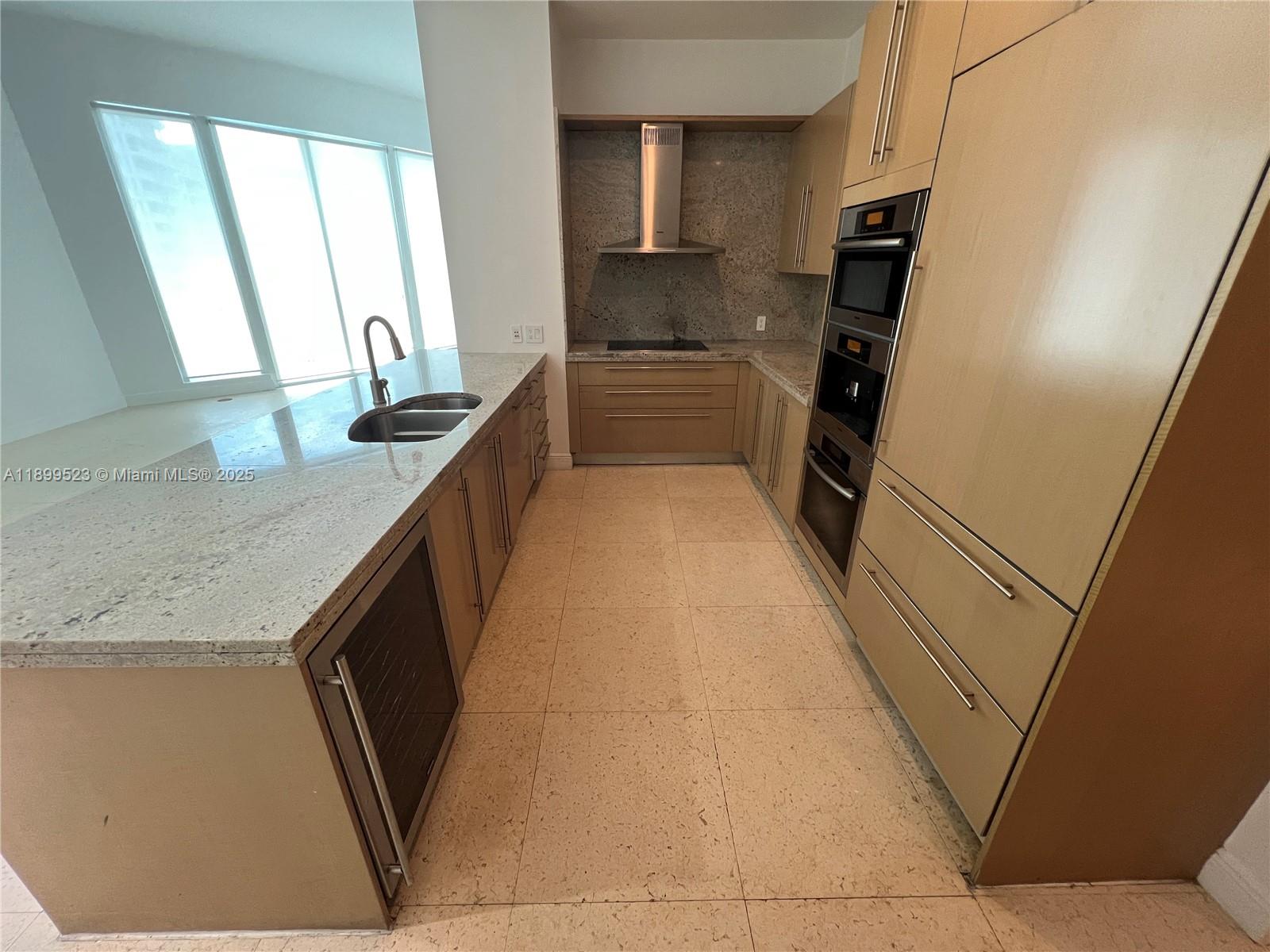 900 Brickell Key Boulevard, Unit 2205 Miami, FL 33131 - Photo 10 of 50 a kitchen with granite countertop a sink a refrigerator and a stove