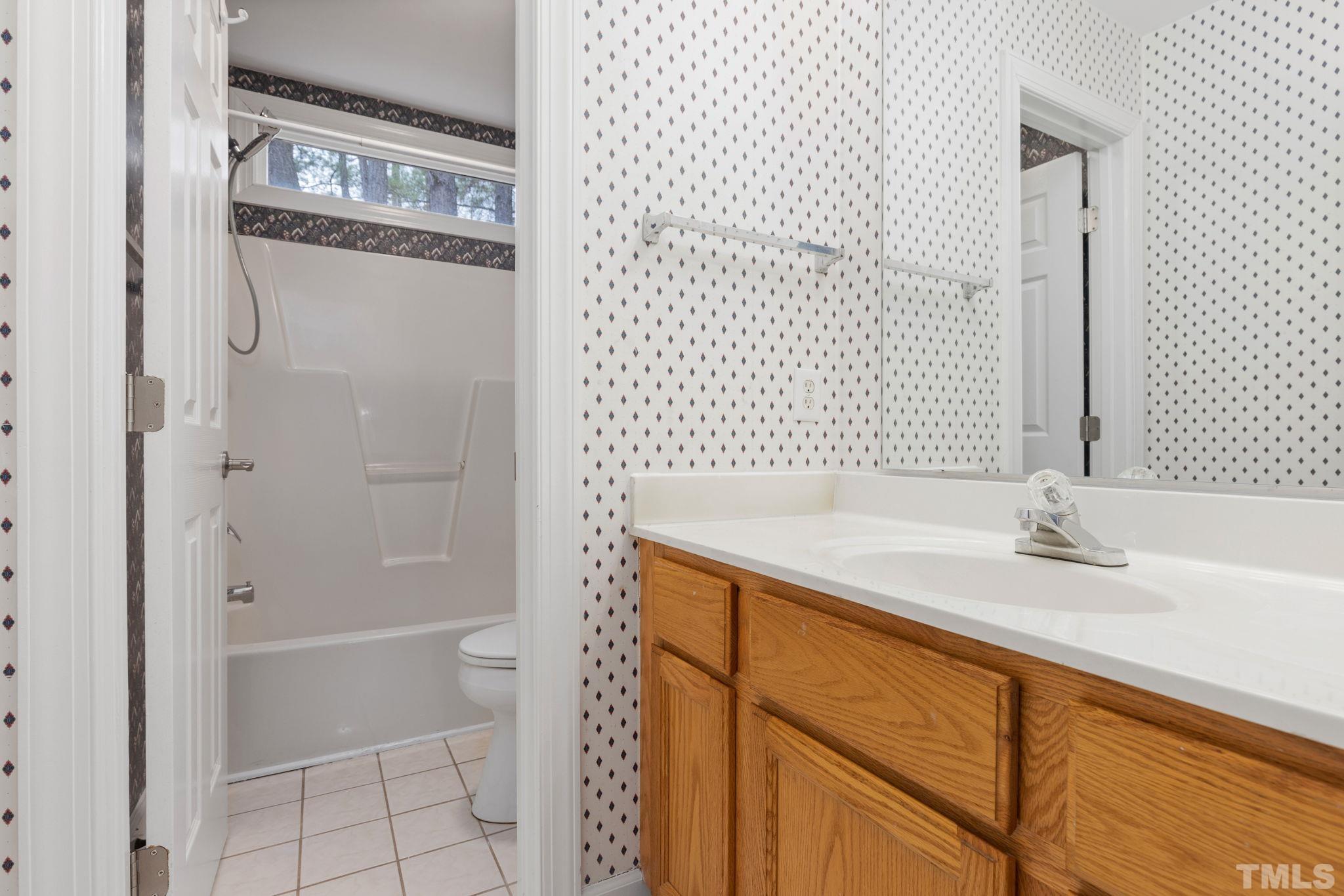 4313 Timberwood Drive Raleigh, NC 27612 - Photo 25 of 28 a bathroom with a granite countertop sink a toilet and shower